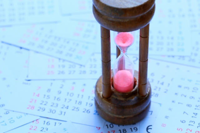ピンク色の砂時計とカレンダーの写真