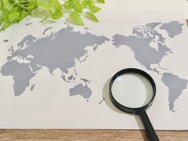 世界地図と上に置かれた虫眼鏡と観葉植物
