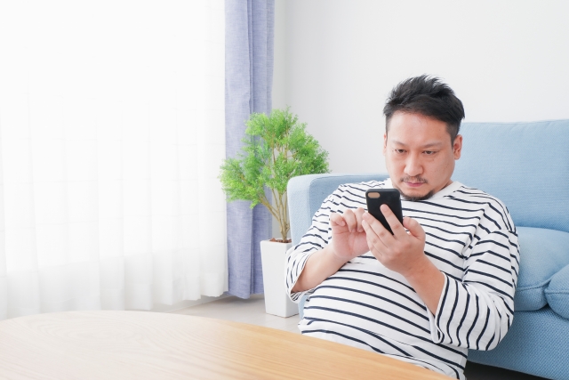 部屋で男性がスマホ見てる