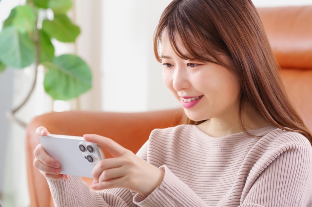 笑顔の女性がスマホを横向きに持っている