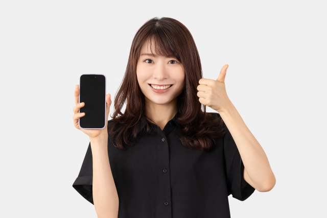 女性が笑顔でスマホを持っている