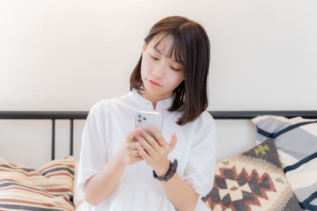 スマホを持った不満げな女性