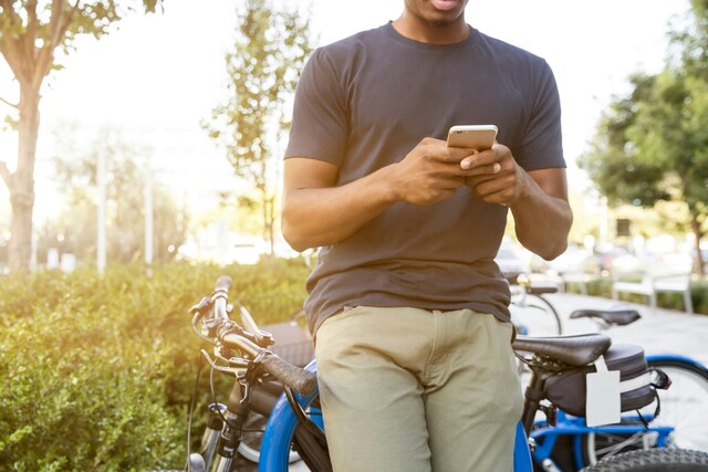 自転車に寄りかかってスマホを持っている男性