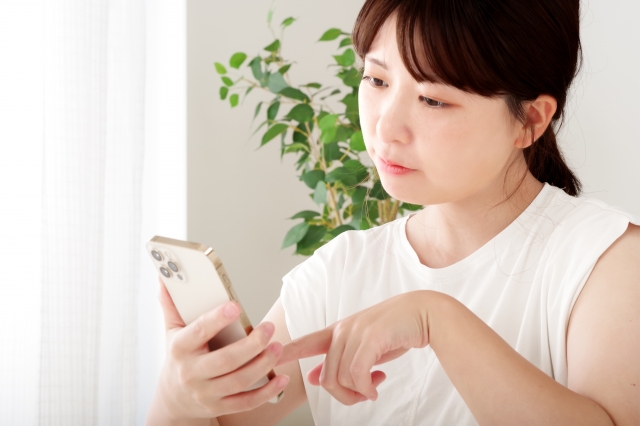 スマホ片手に悩む女性