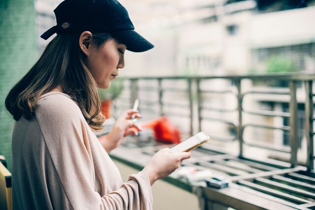 スマホを手に持って立っている女性