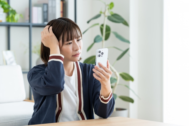 スマホを持って心配そうな顔の女性