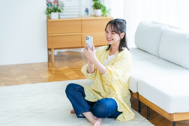 部屋でスマホを操作する女性