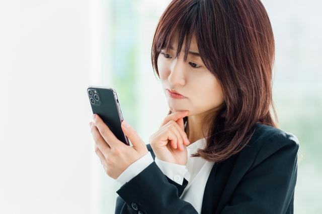 スマホを持って悩んでいる女性