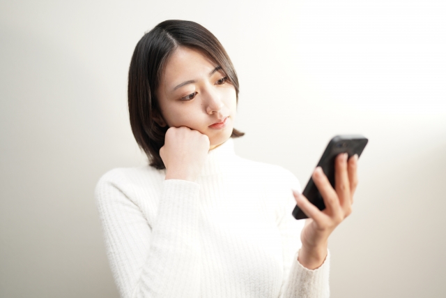 女性がスマホ片手に困った顔